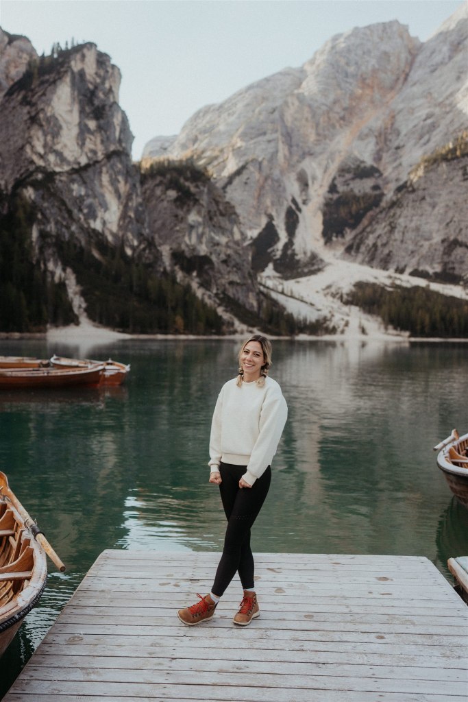 Lifestyle and travel photographer standing on a dock by the lake in the Dolomite mountains